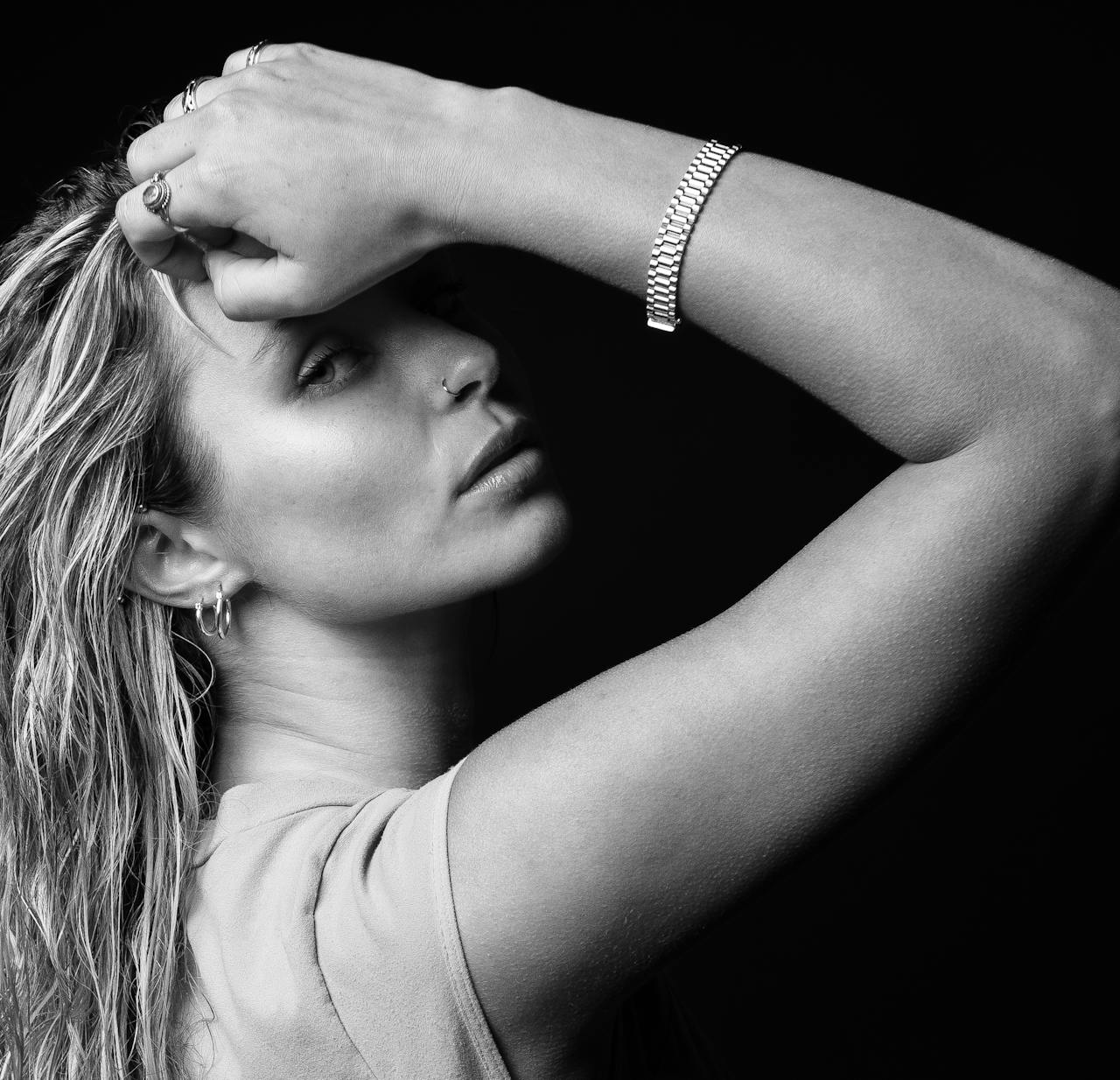 Home Elegant black and white portrait of a woman with arm raised, highlighting jewelry and facial features.
